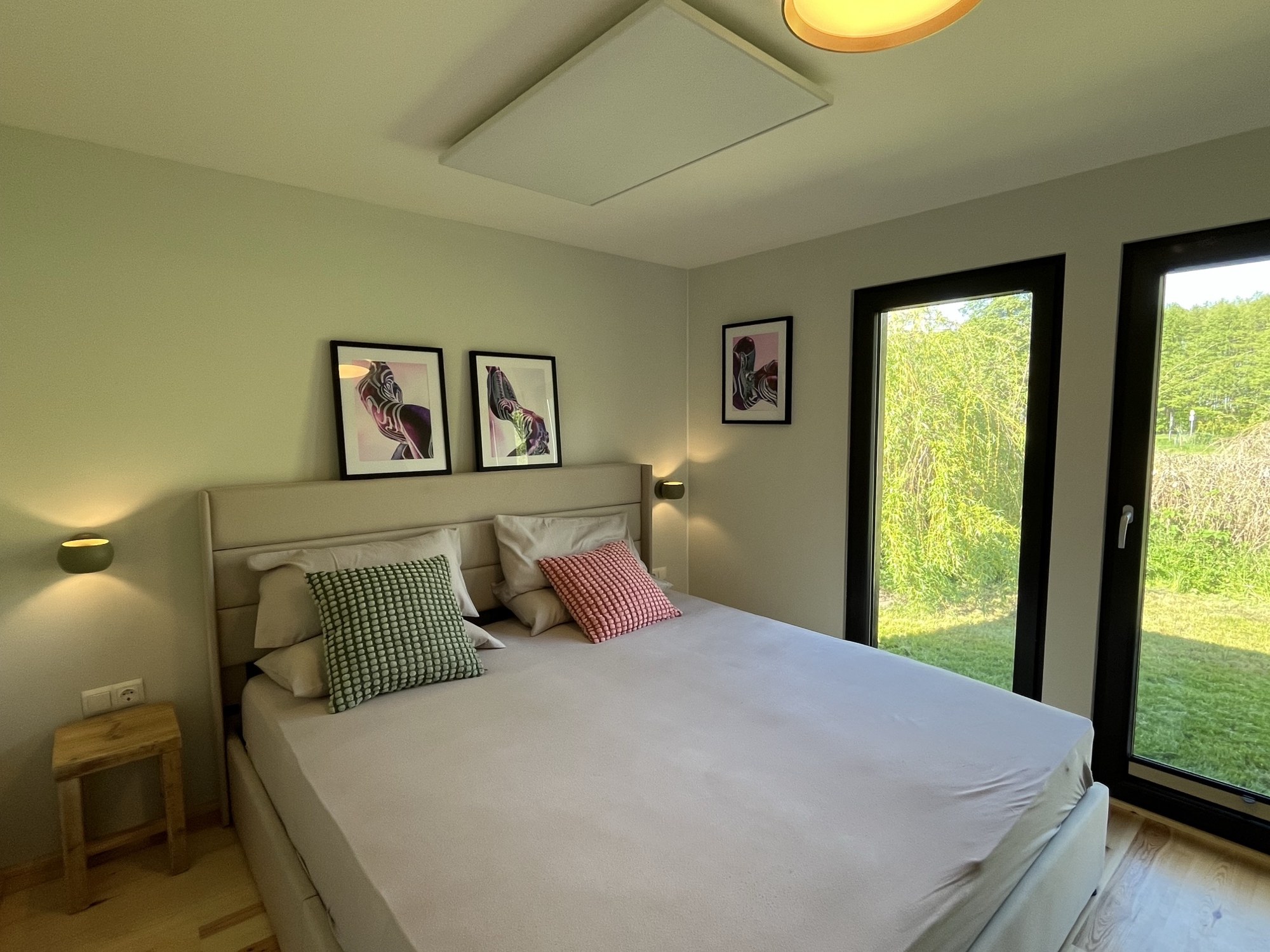 Schlafzimmer mit Doppelbett und bodentiefen Fenstern zur Wiese