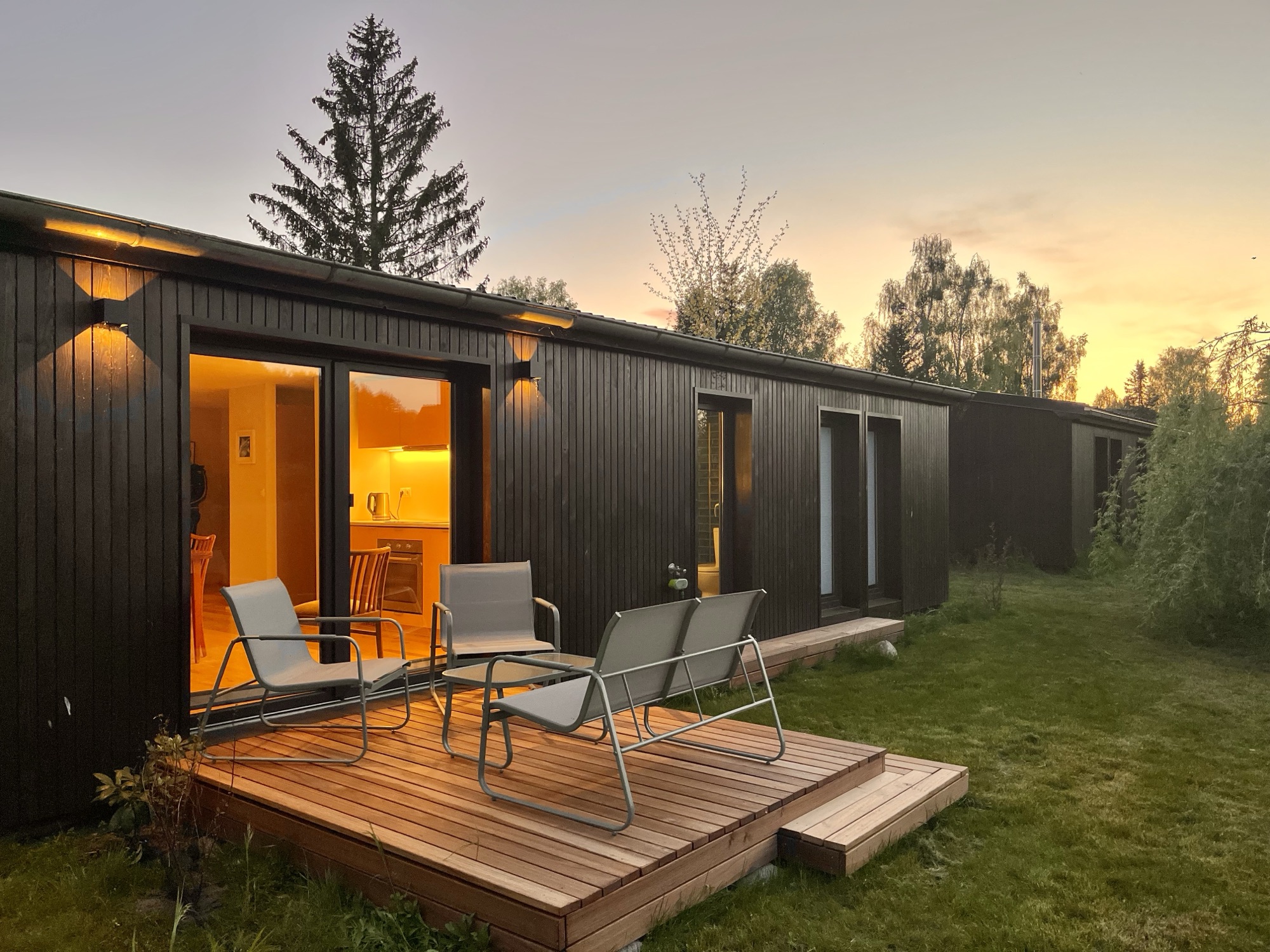 Terrasse von Haus 1 mit Sesseln vor dem beleuchteten Bungalow