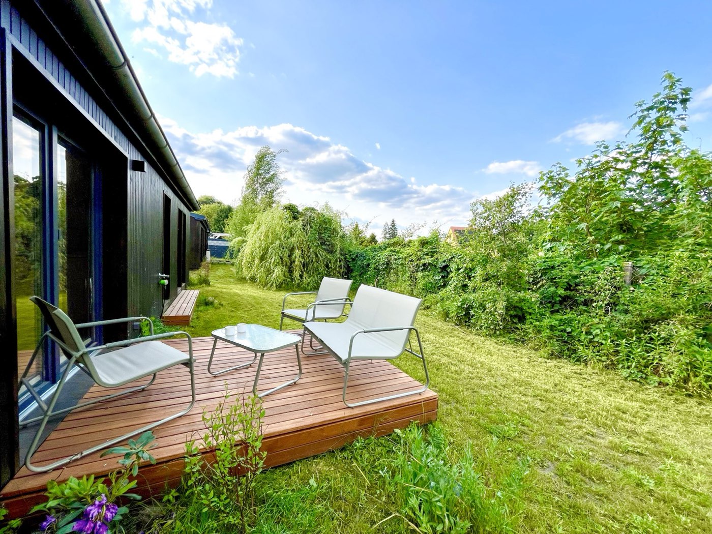 Holzterrasse mit Sitzgruppe im grünen Garten