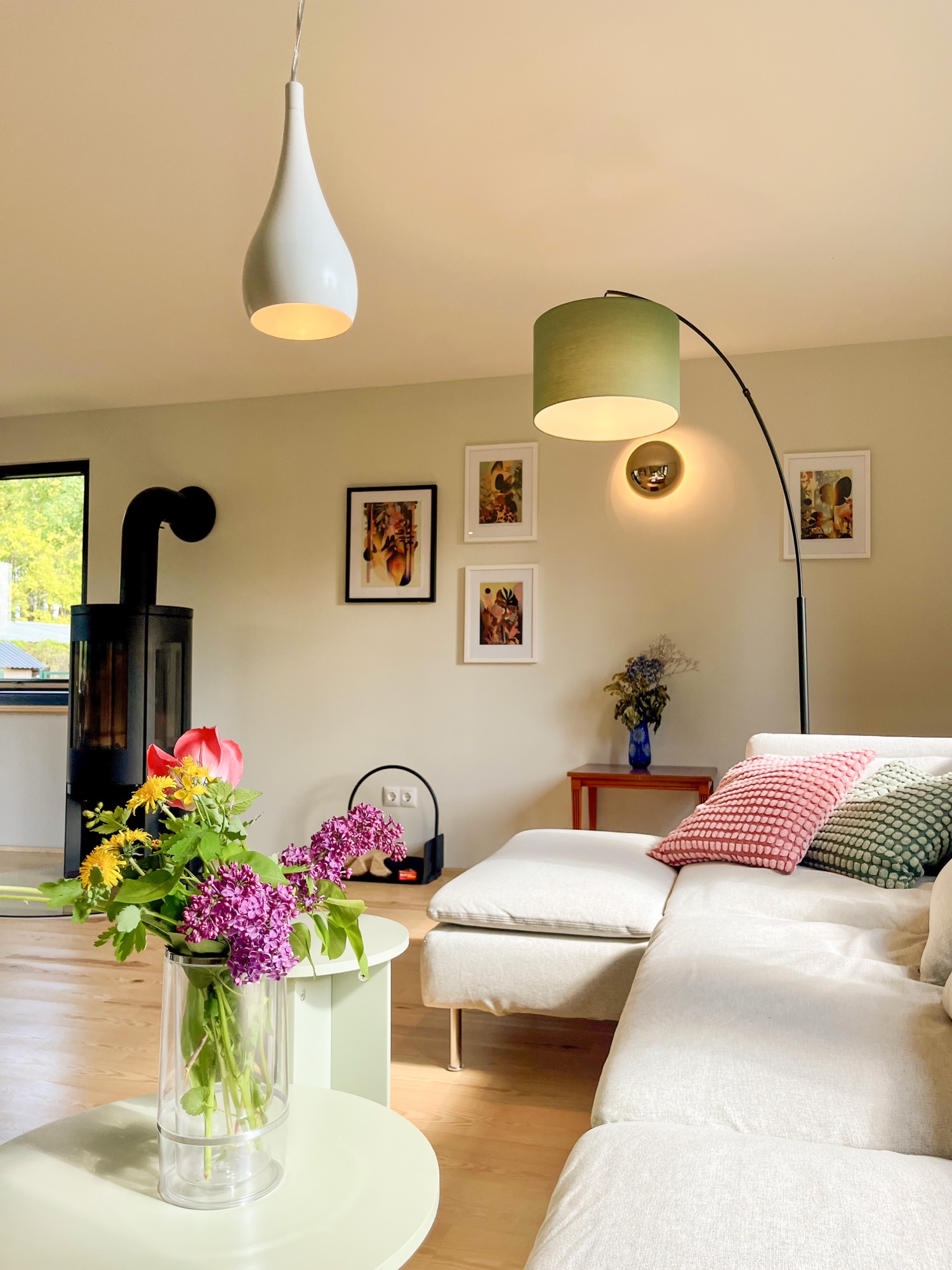 Wohnbereich mit Bogenlampe, Kaminofen und Blumenstrauß