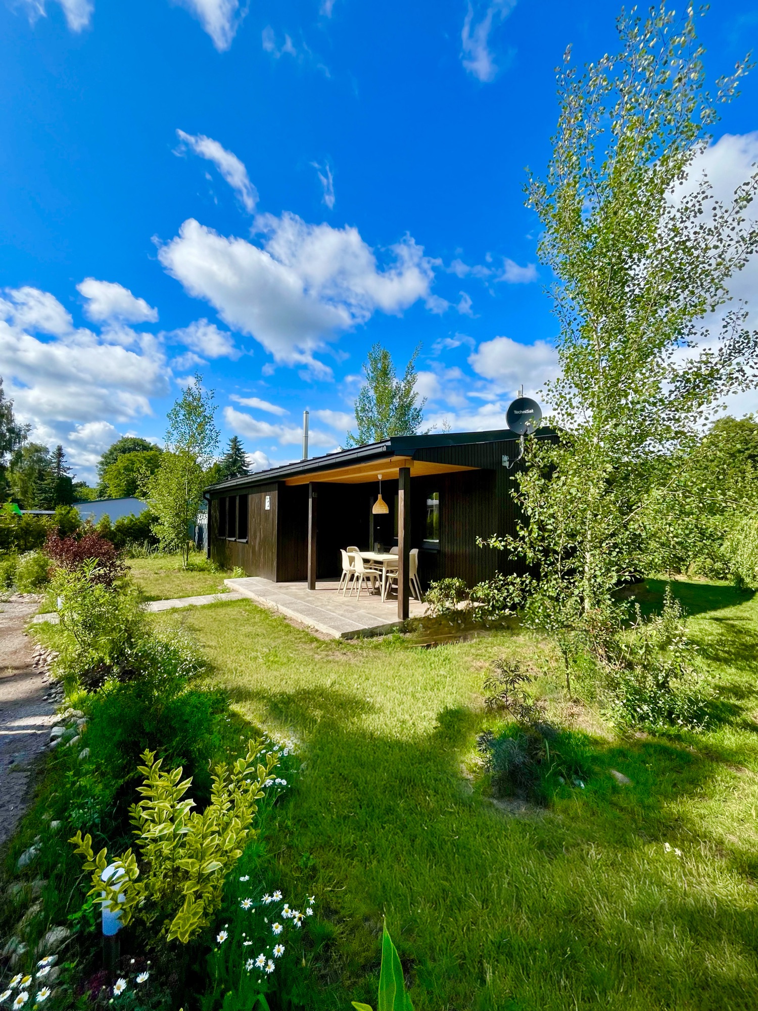 Haus 2 mit überdachter Veranda unter blauem Sommerhimmel