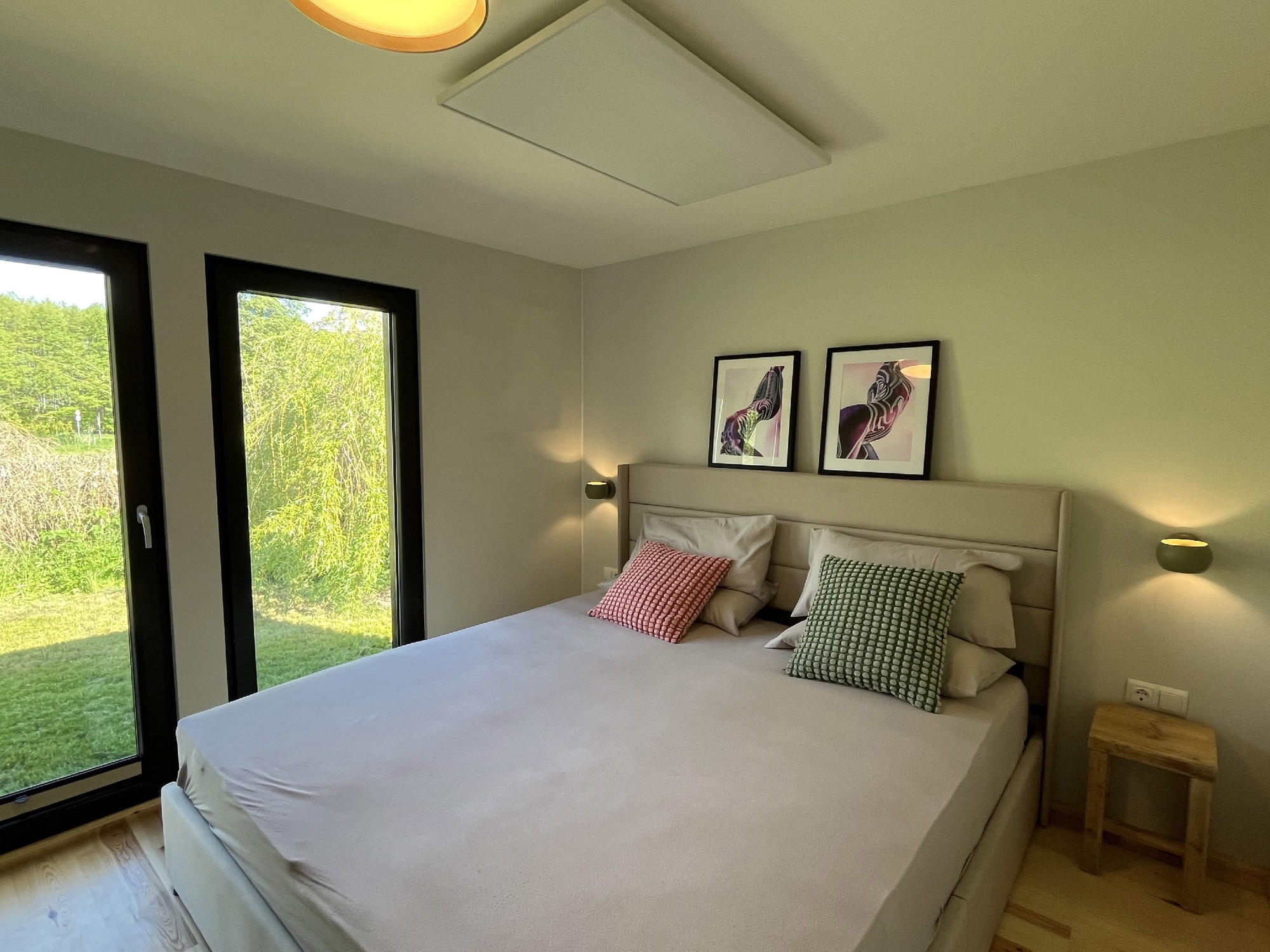 Schlafzimmer von Haus 2 mit bodentiefen Fenstern zur Wiese