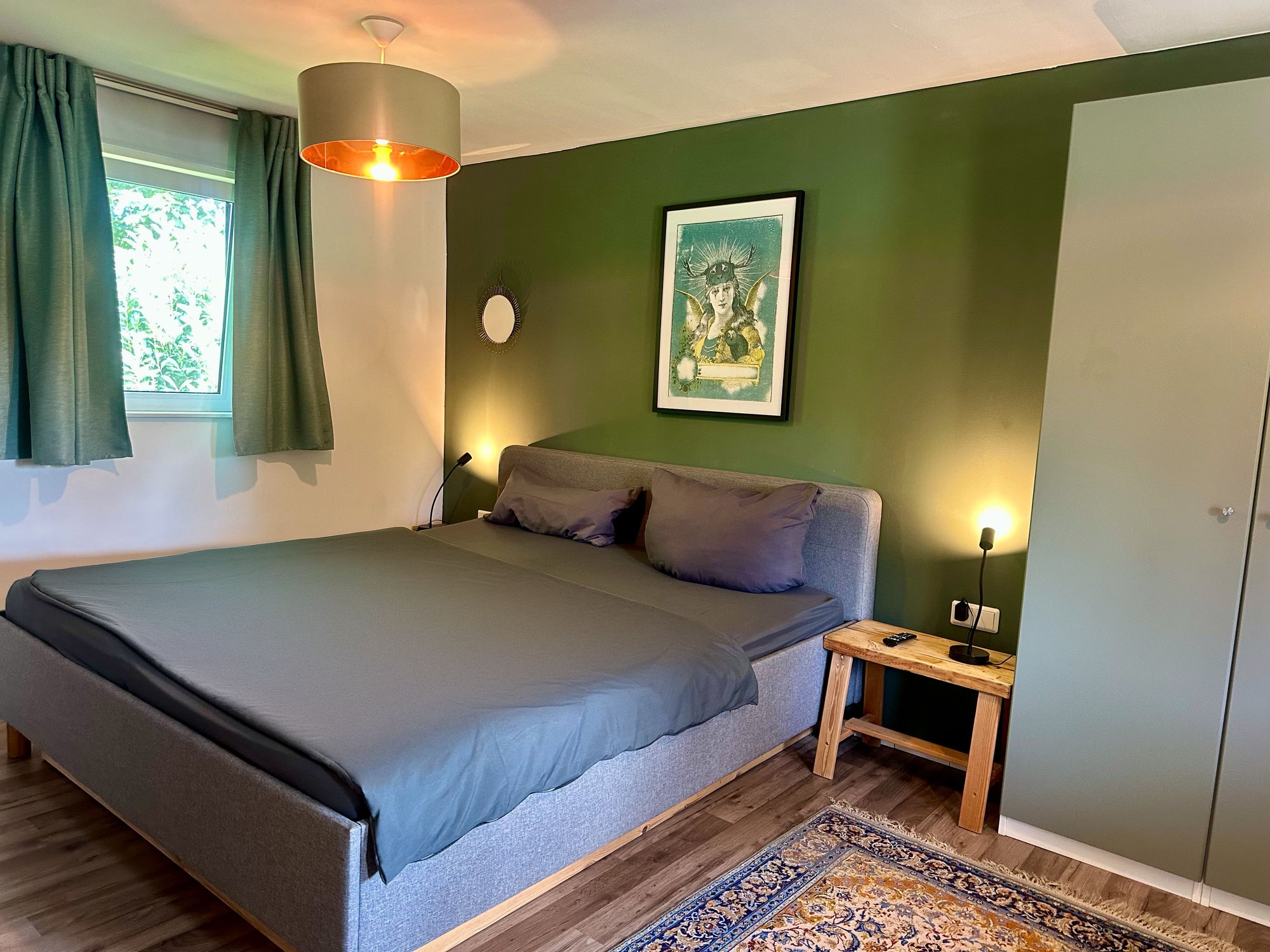 Schlafzimmer von Haus 8 mit Doppelbett vor grüner Wand