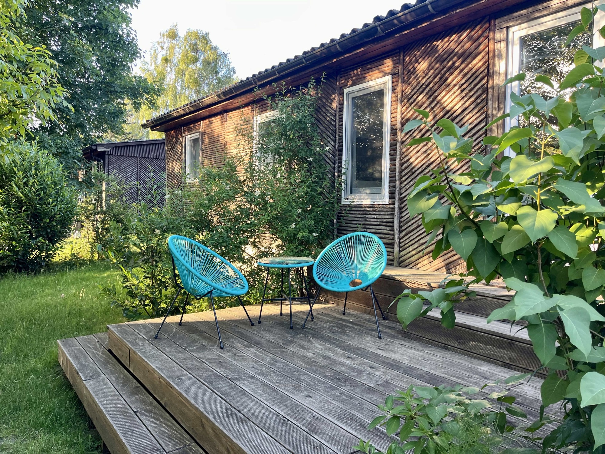 Holzterrasse von Haus 8 mit türkisen Sesseln