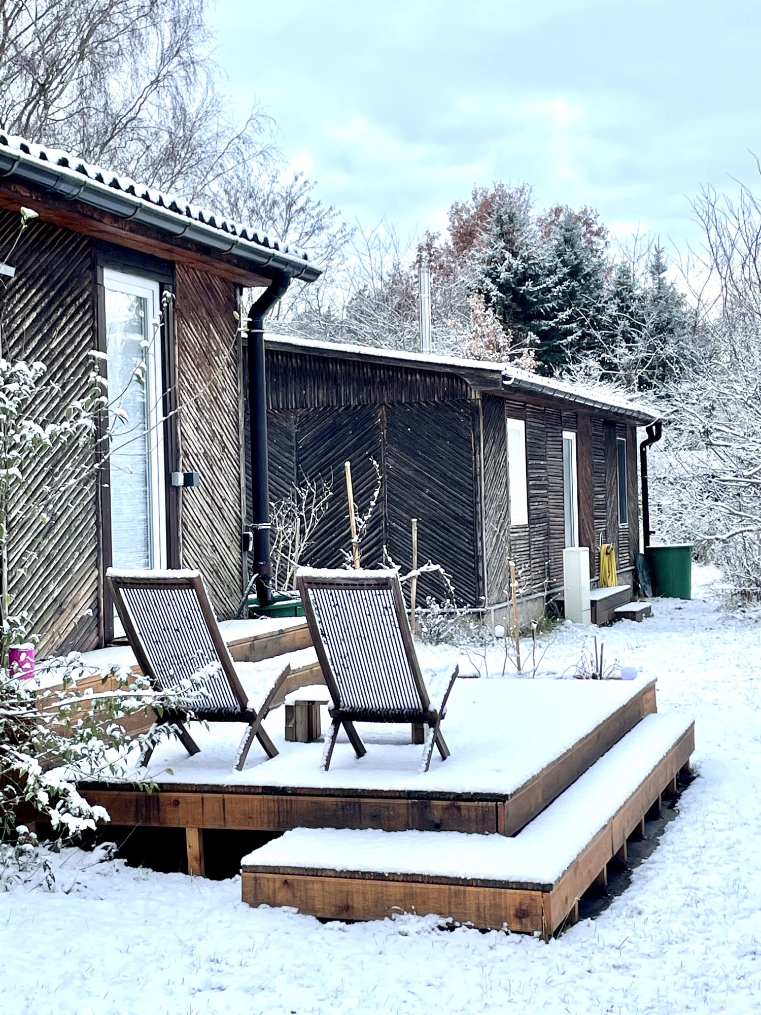 Verschneite Terrasse von Haus 8 mit Liegestühlen