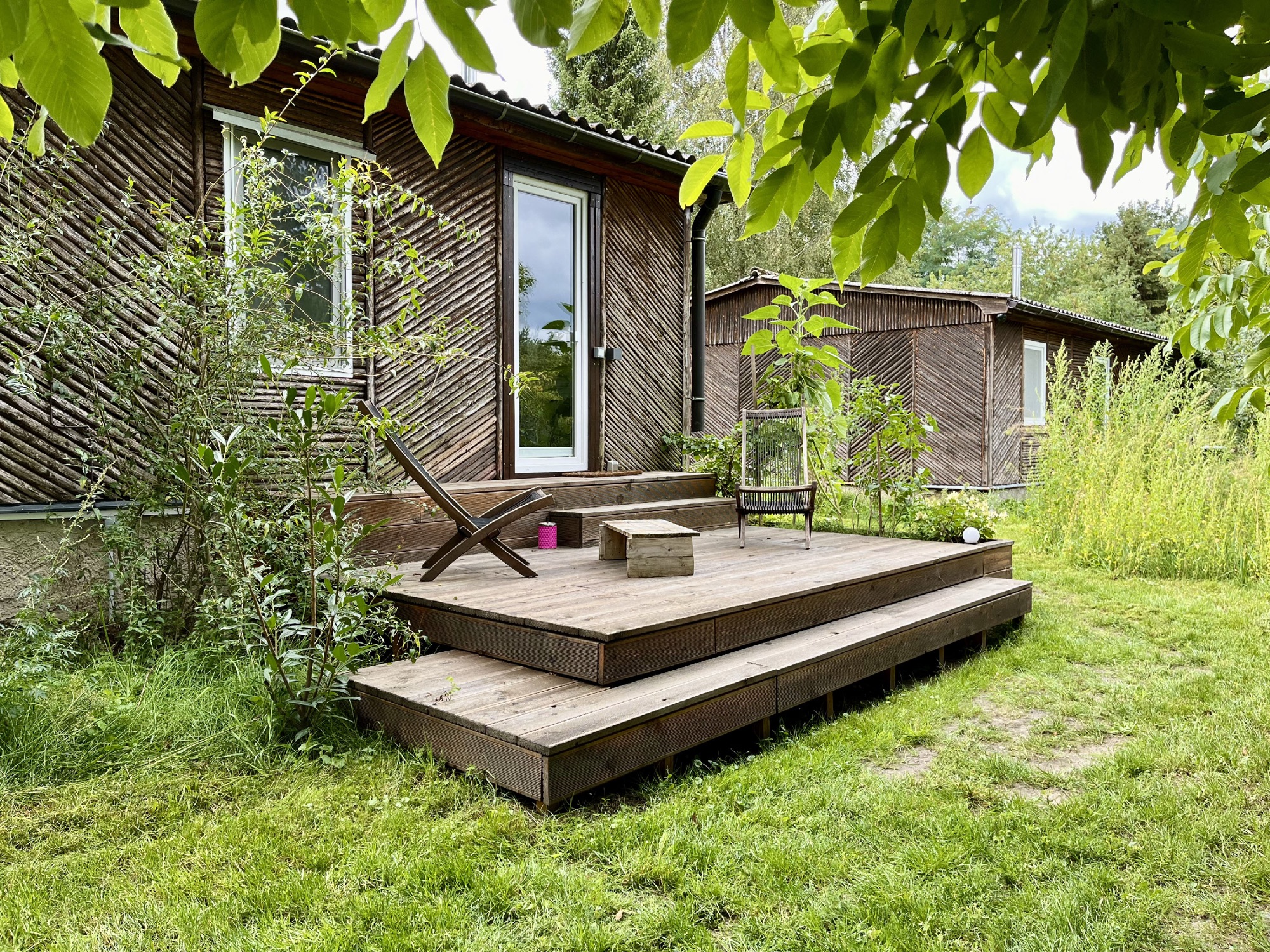 Holztreppe zur Veranda von Haus 8 im Sommergrün